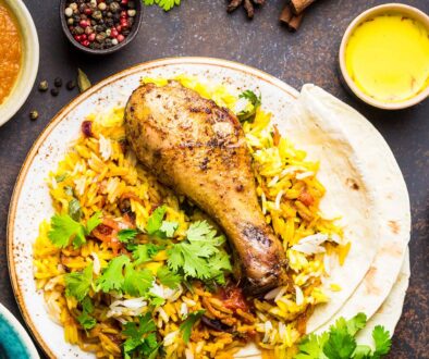 A table spread with chicken biryani, condiments, and side dishes