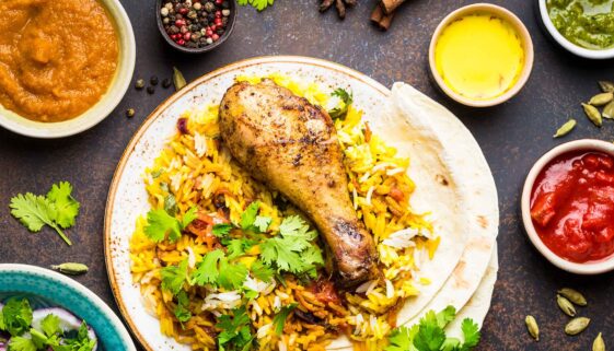 A table spread with chicken biryani, condiments, and side dishes